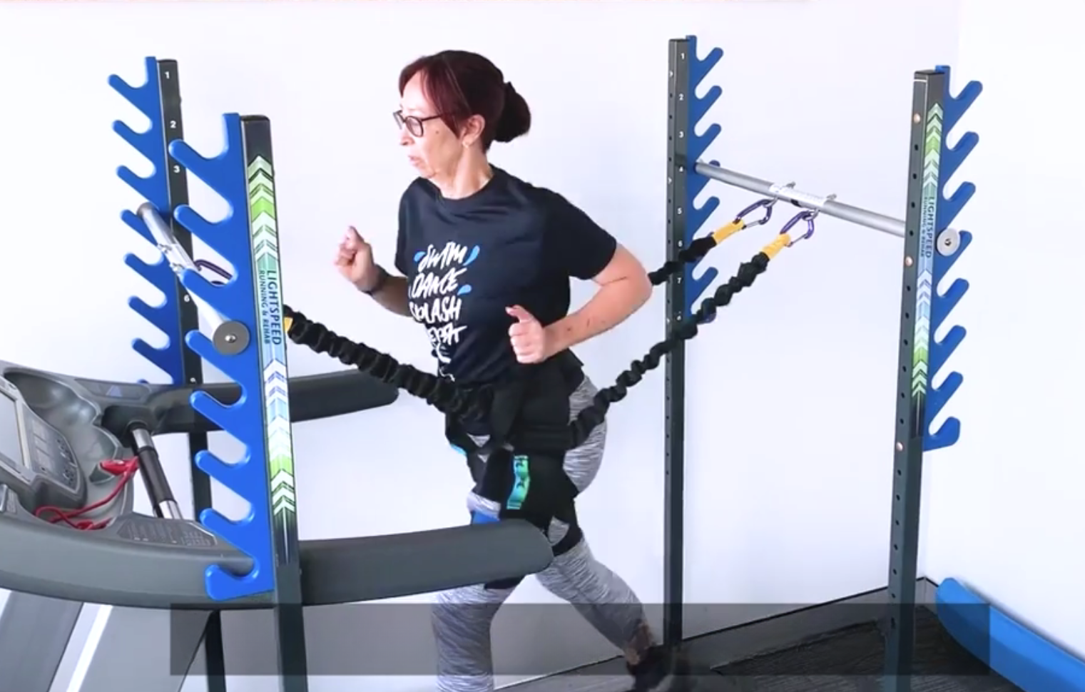 A woman is using a specialised treadmill with resistance bands attached, demonstrating an exercise routine at My Health Team.