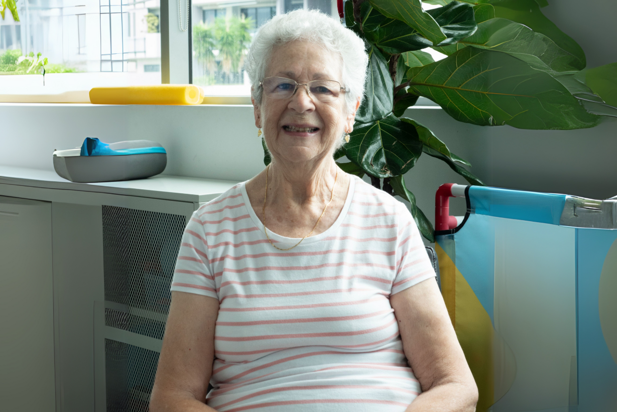  An older woman with white hair and glasses sitting smiling straight into the camera